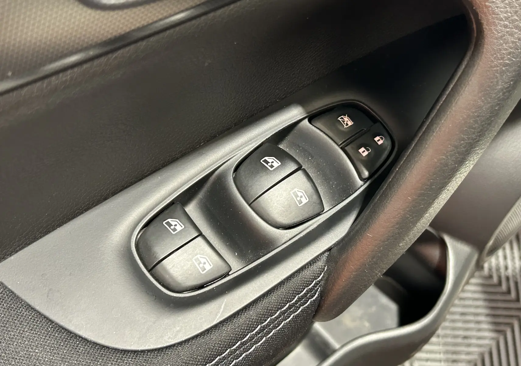 Gros plan sur les commandes de lève-vitres et verrouillage sur la portière côté conducteur du Nissan Qashqai blanc 2018.