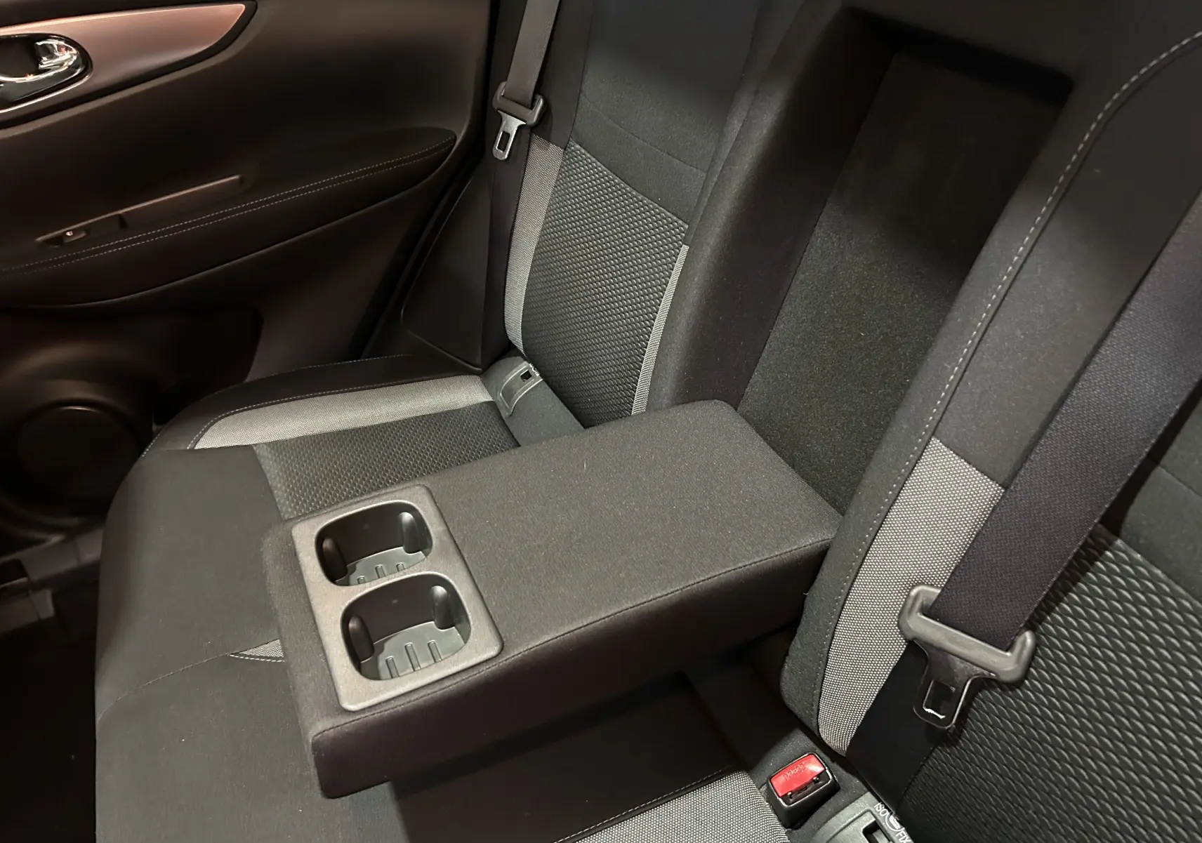 Vue rapprochée de la banquette arrière du Nissan Qashqai 2018 avec accoudoir central et porte-gobelets intégrés.