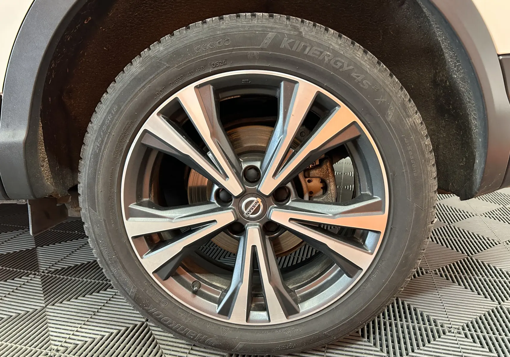 Gros plan sur la roue avant gauche du Nissan Qashqai blanc avec jante alliage bicolore et pneu Hankook.