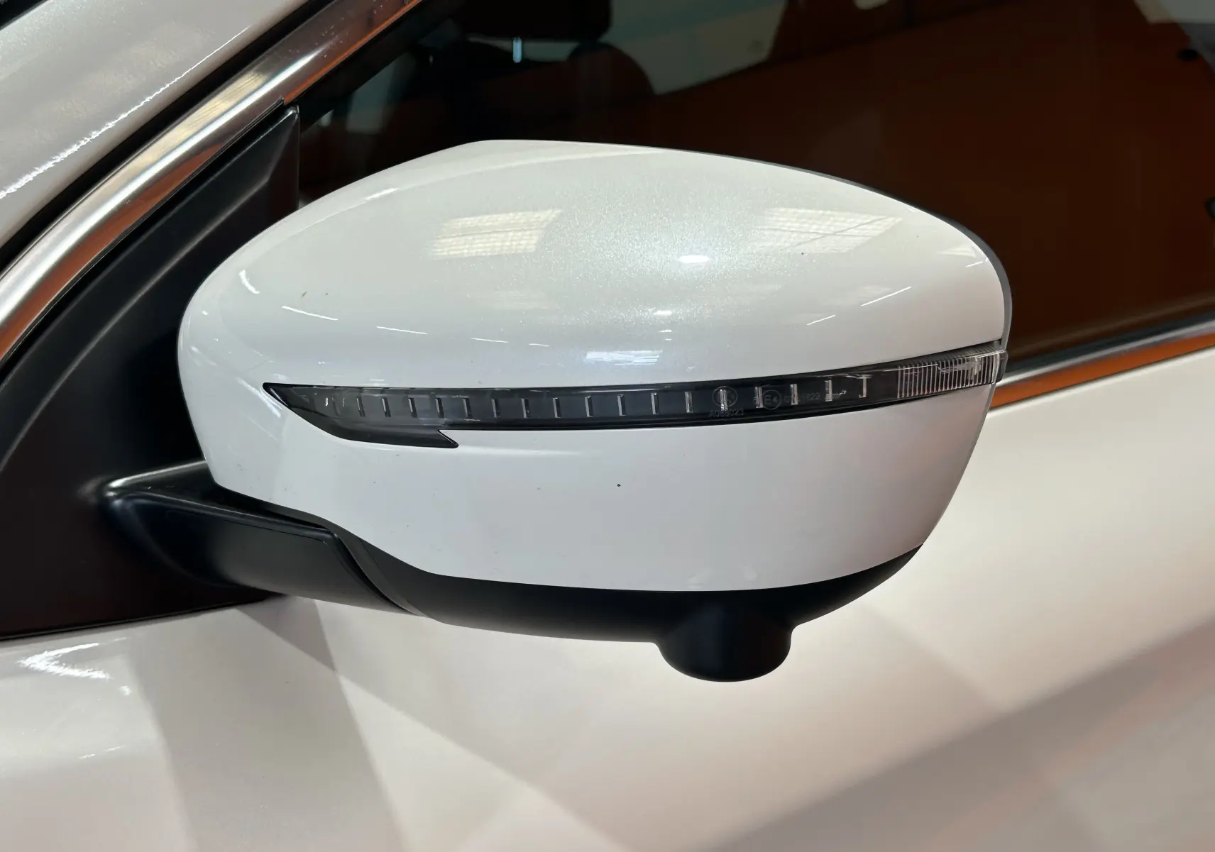 Rétroviseur droit blanc du Nissan Qashqai 2018 avec clignotant intégré, vue rapprochée sur fond intérieur sombre.