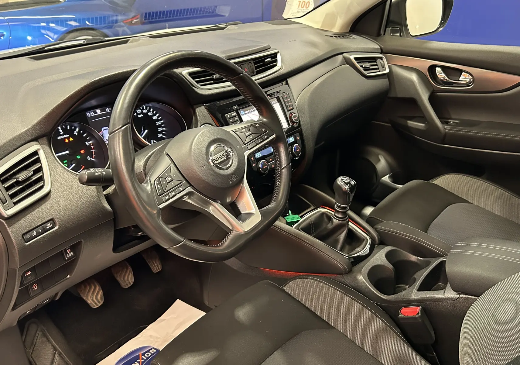 Vue intérieure côté conducteur du Nissan Qashqai 2018, tableau de bord noir avec volant cuir et boîte manuelle.