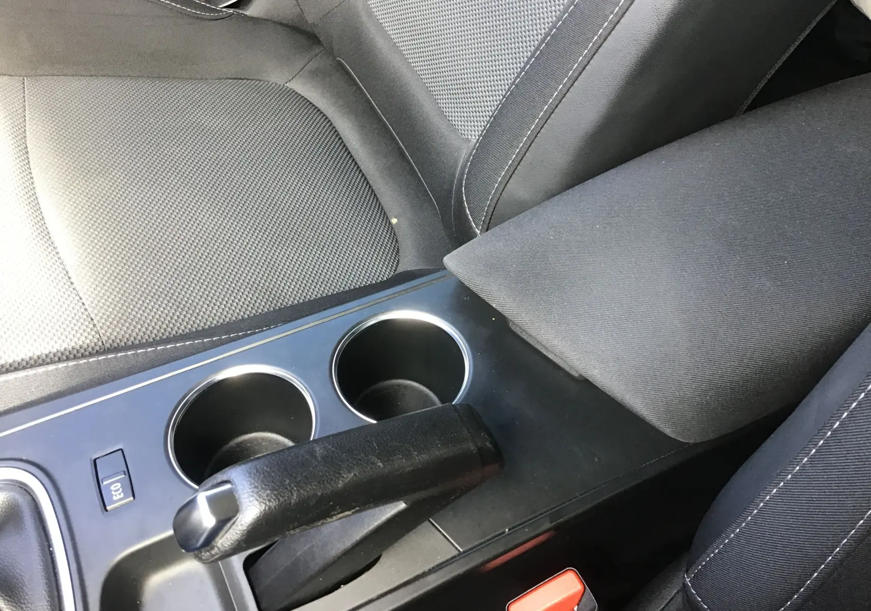 Gros plan sur la console centrale noire et les sièges tissu gris foncé de la Renault Mégane IV Société blanche, version 2021.
