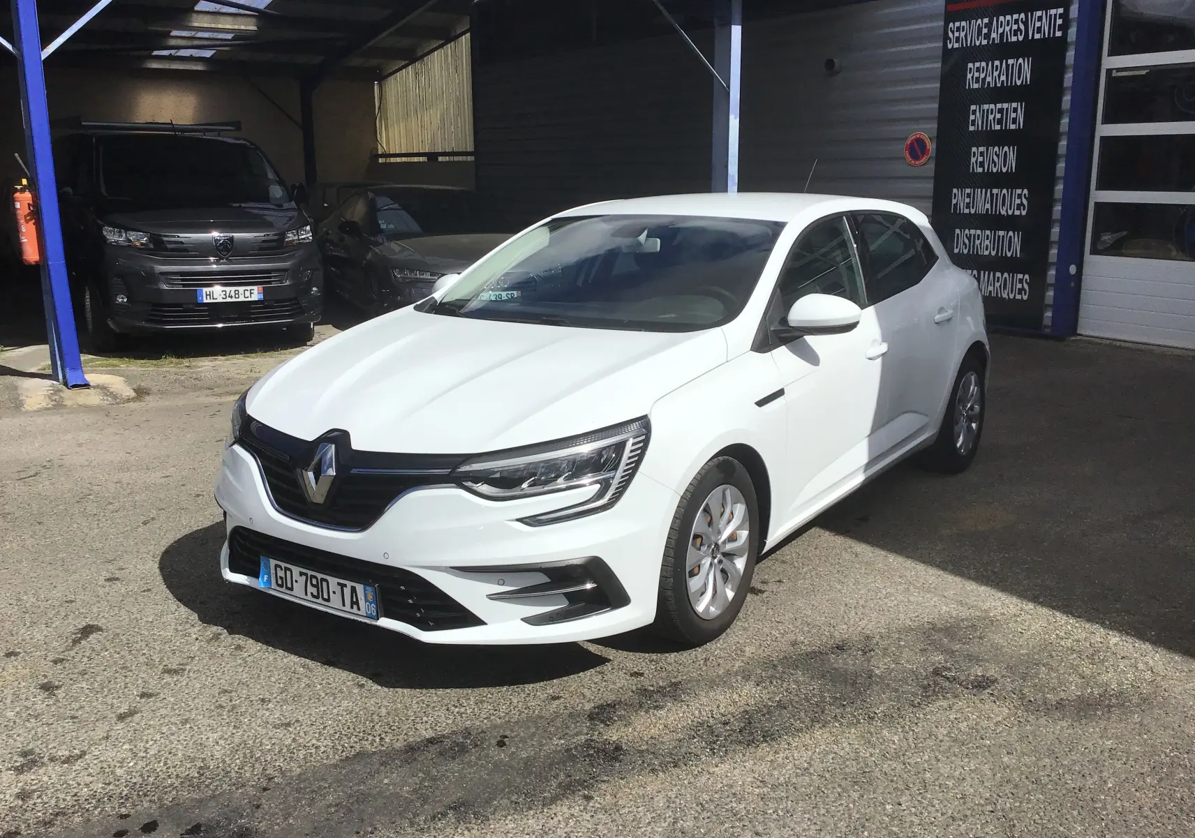 Renault Mégane IV Société blanche vue en 3/4 avant droit, avec calandre noire et phares LED distinctifs.