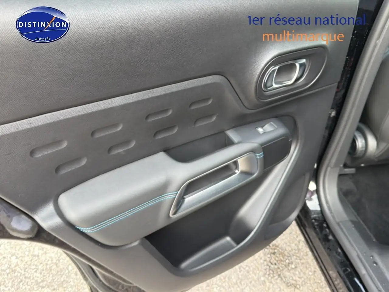 Gros plan sur la porte avant gauche noire perla nera du Citroën C5 Aircross avec surpiqûres bleues et poignée intégrée.