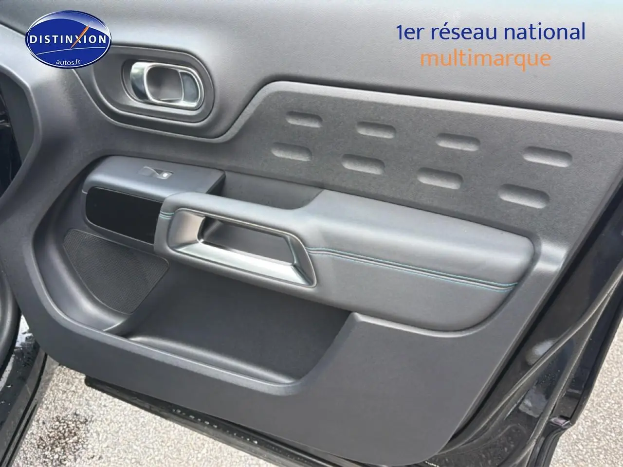 Intérieur de la porte avant gauche du Citroën C5 Aircross noir Perla Nera avec poignée argentée et surpiqûres bleues.