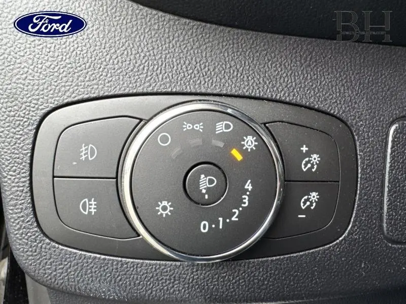 Gros plan sur le sélecteur de réglage des phares du Ford Puma 2023, avec surface noire texturée et indicateur lumineux orange.