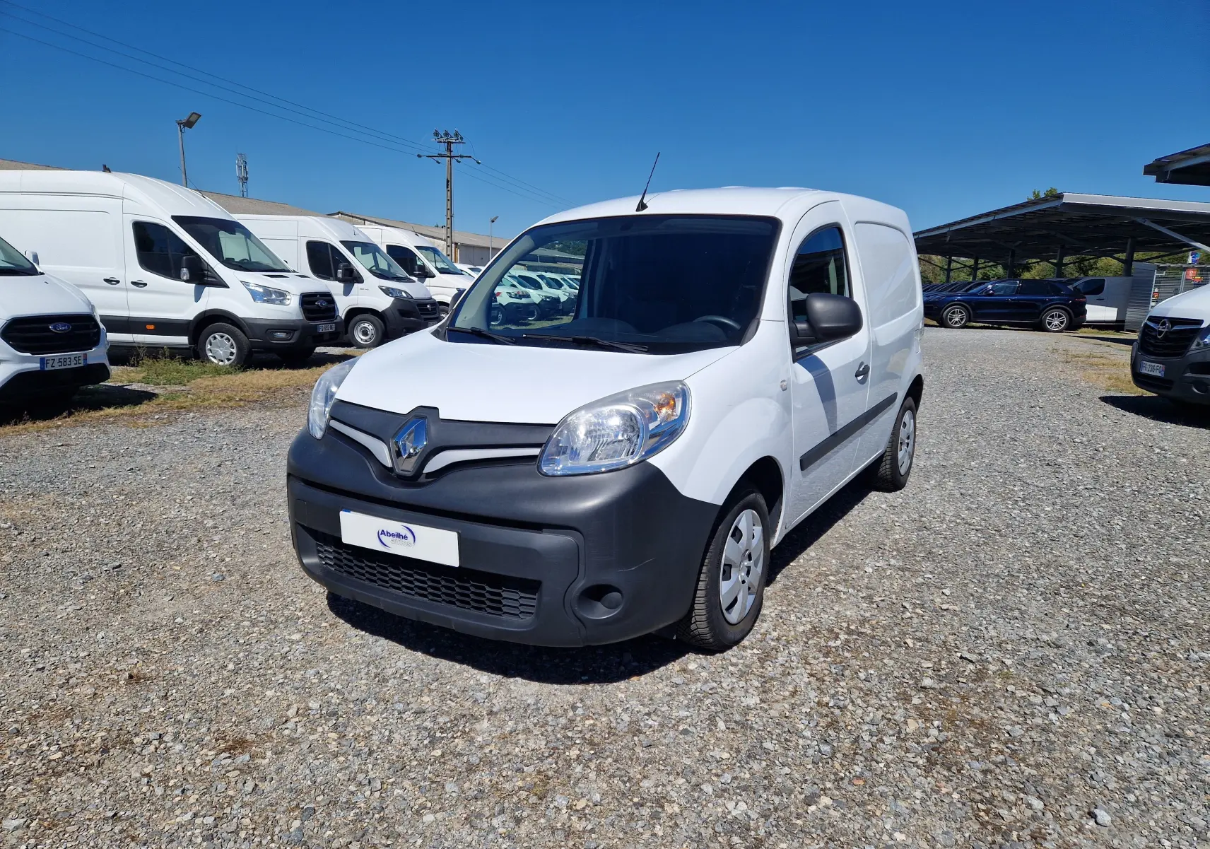 Renault Kangoo blanc vue 3/4 avant droit, fourgonnette utilitaire avec pare-chocs noir mat et jantes acier.