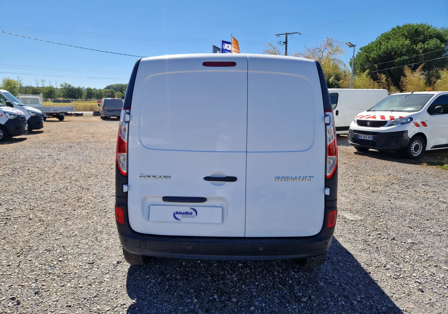 Renault Kangoo blanc vue 3/4 arrière droit, fourgonnette utilitaire avec portes arrière battantes et pare-chocs noirs.
