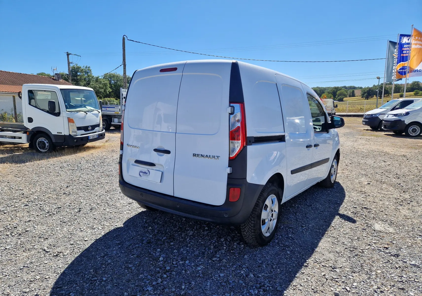 Vue intérieure arrière du coffre blanc du Renault Kangoo 1.5 Blue dCi 80 Extra, montrant un espace utilitaire vide avec parois en bois.