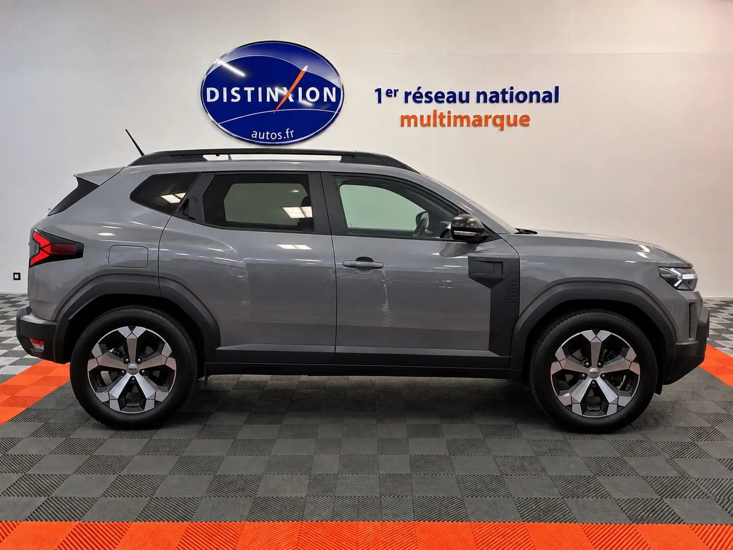 Profil latéral droit du Dacia Duster 2026 gris schiste avec jantes alliage et détails noirs contrastants.