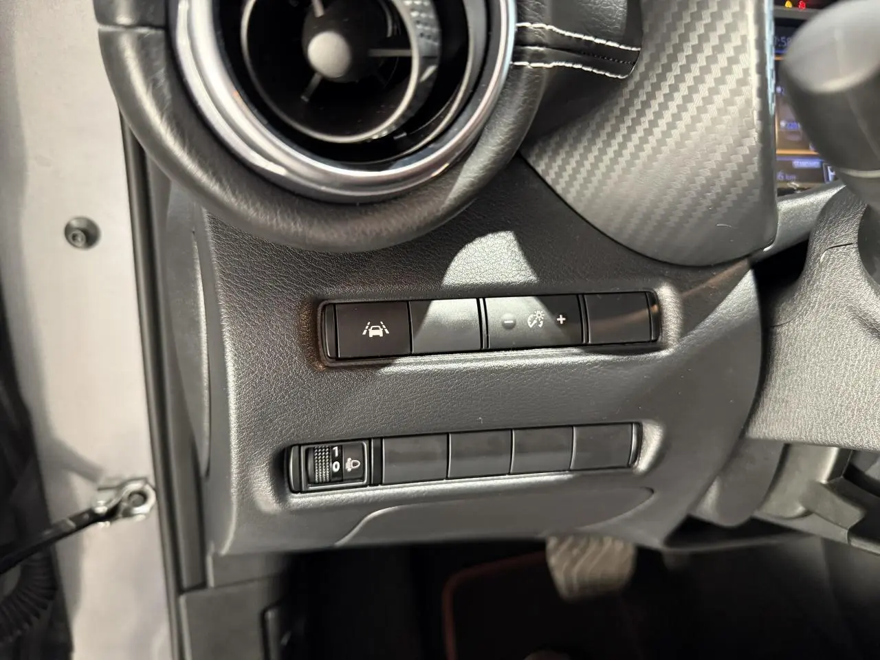 Gros plan sur les commandes d'aides à la conduite côté gauche du tableau de bord noir du Nissan Juke Hybrid 2024.