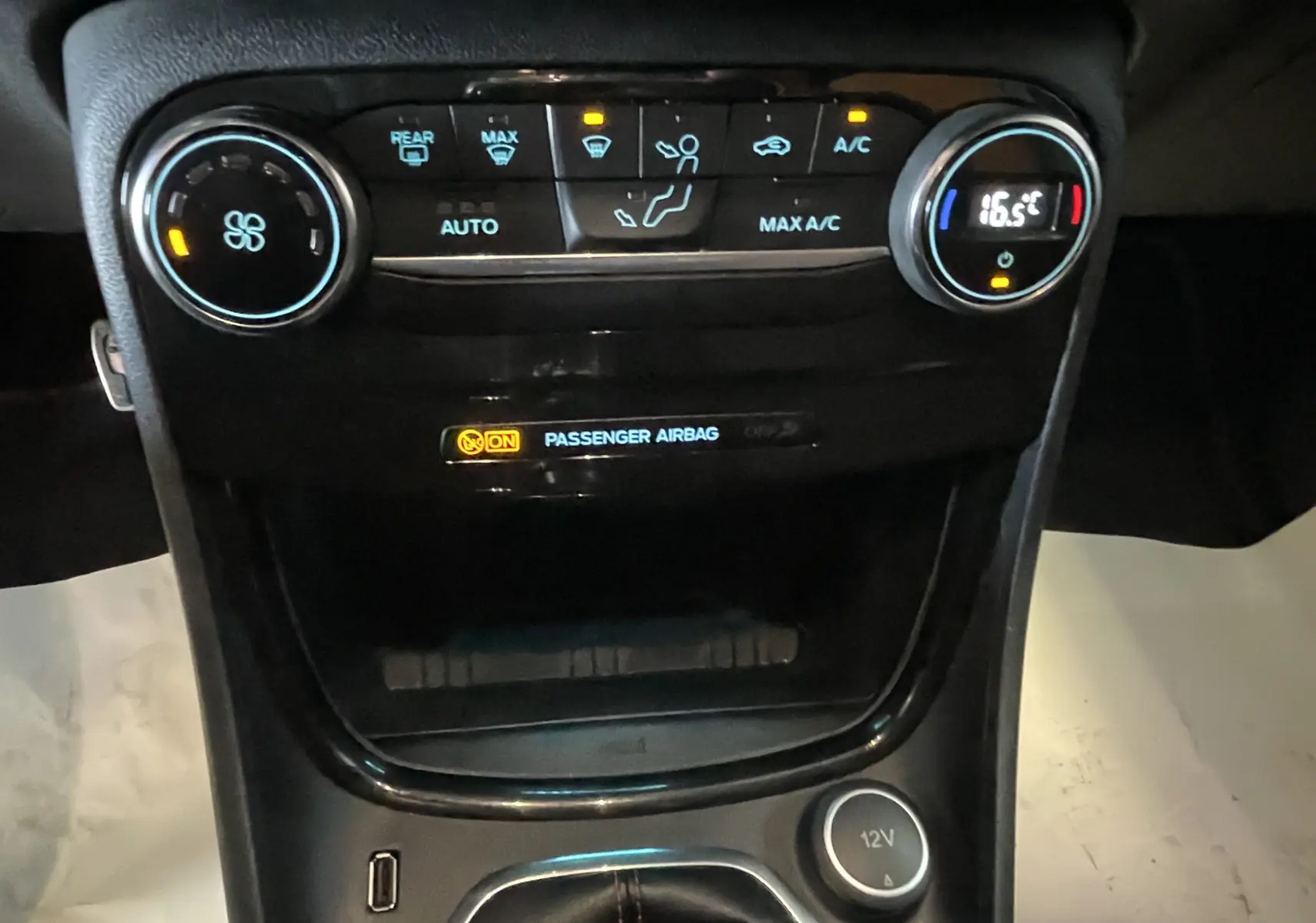 Vue rapprochée de la console centrale du Ford Puma gris, montrant les commandes de climatisation et l'indicateur d'airbag passager.