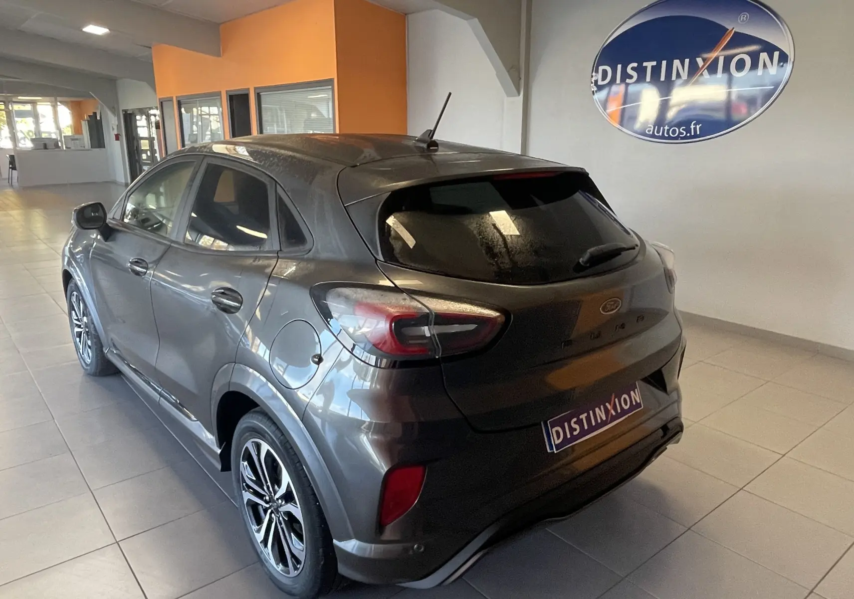 Vue 3/4 arrière droite d'une Ford Puma gris métallisé 2020 en intérieur avec feux arrière LED et jantes alliage.