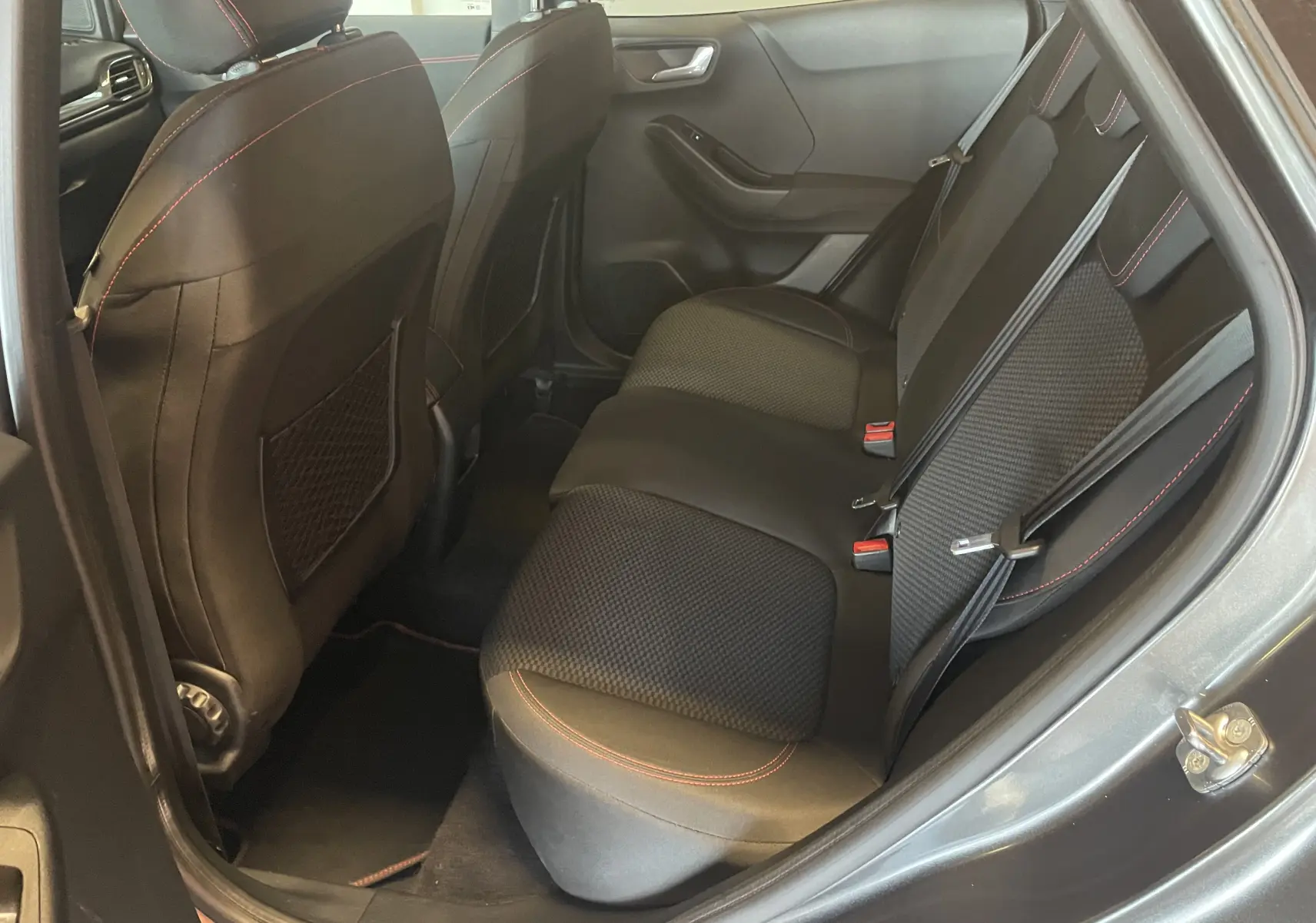 Vue intérieure arrière côté droit du Ford Puma gris 2020, sièges tissu noir avec surpiqûres rouges et ceintures grises.