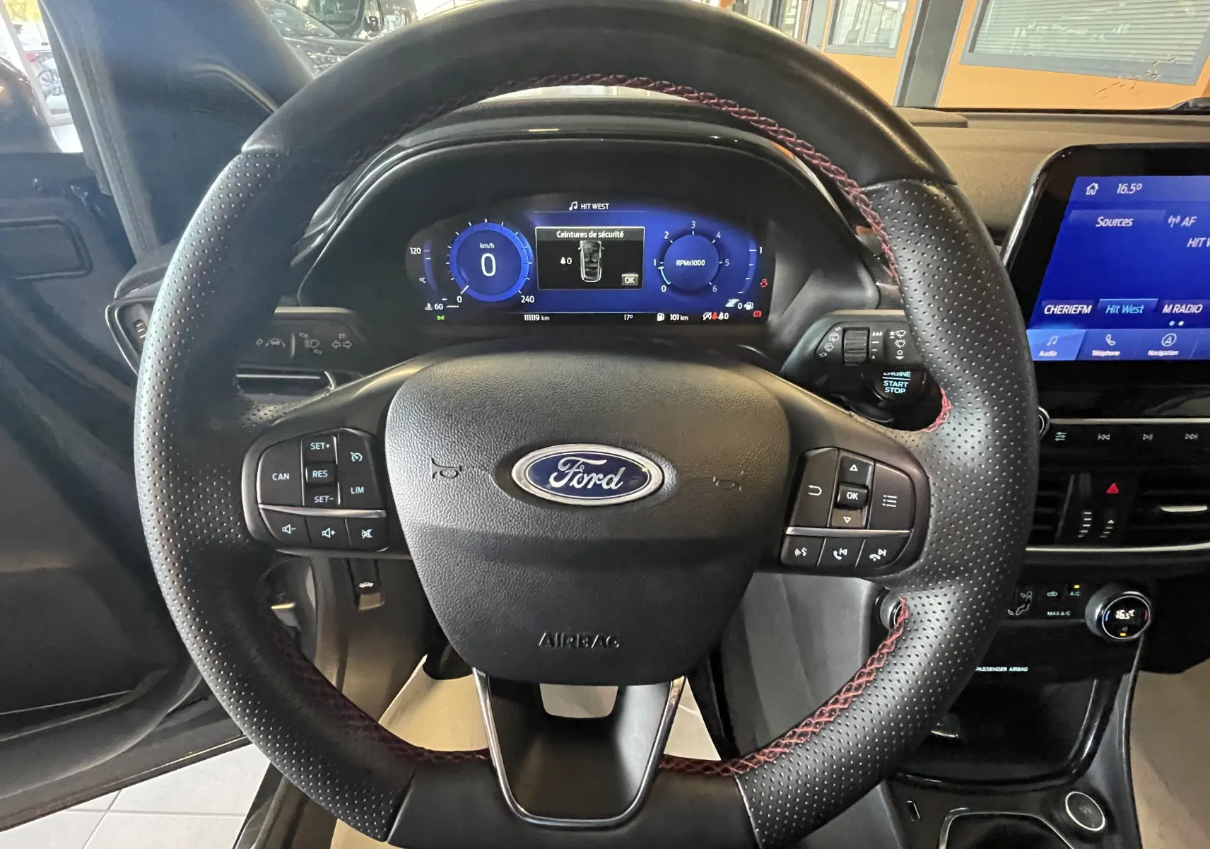 Vue centrée sur le volant noir avec surpiqûres rouges du Ford Puma 2020, tableau de bord numérique et écran tactile visible.