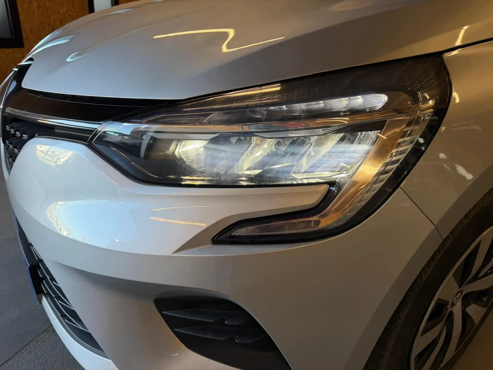 Gros plan sur le phare avant droit gris platine d'une Renault Clio 1.0 TCE 90 Équilibre 2023 avec calandre noire.