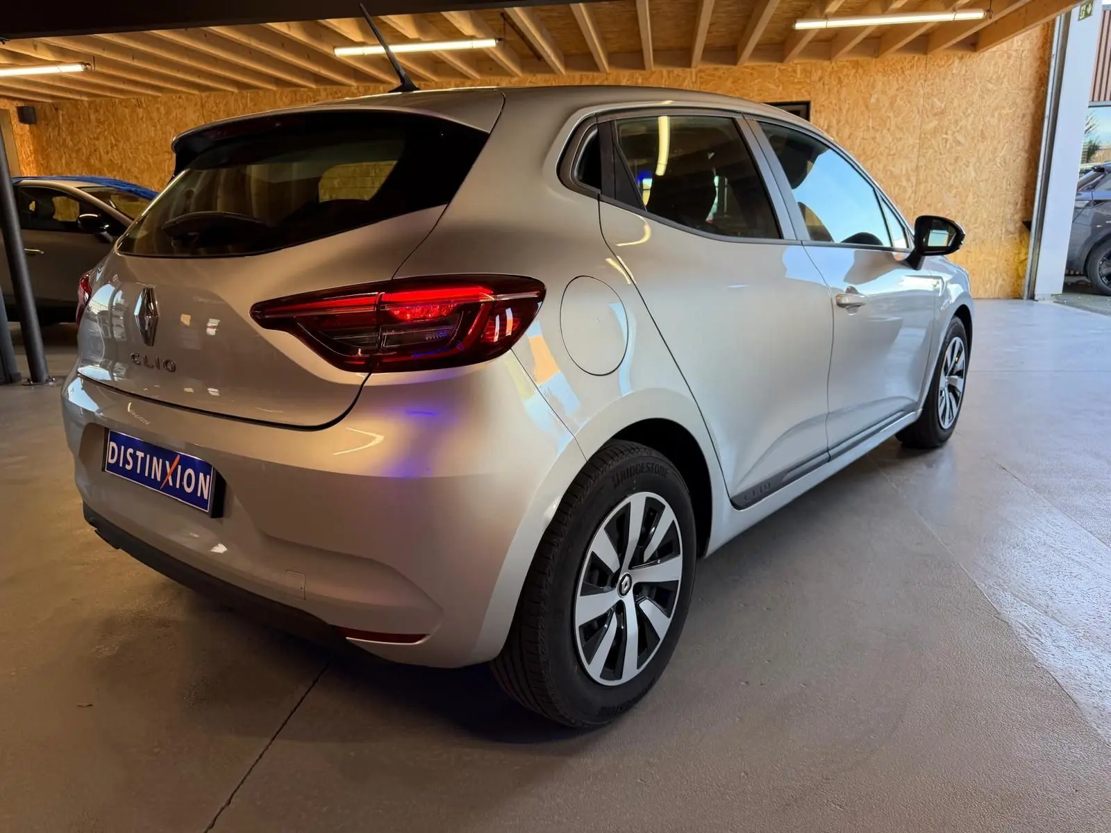 Vue 3/4 arrière droite d'une Renault Clio gris platine 2023 avec feux arrière LED et jantes alliage.