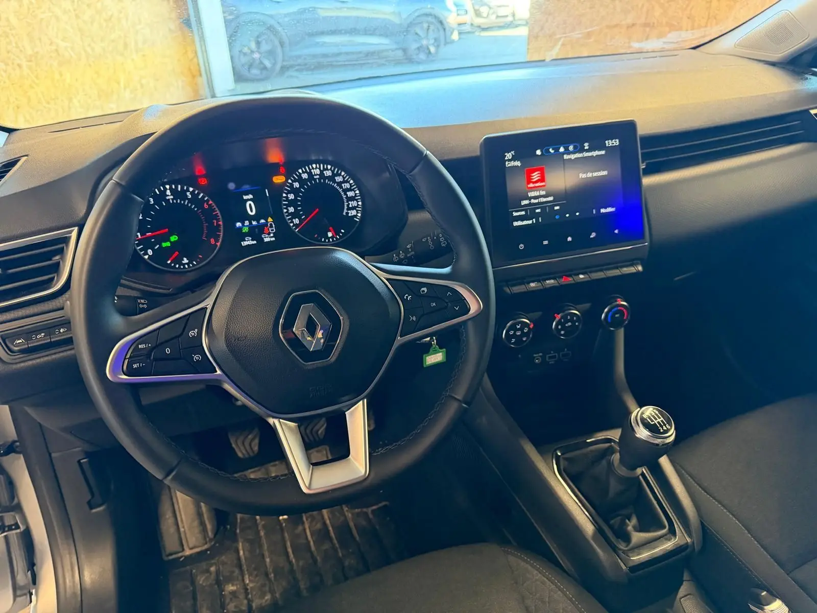 Vue intérieure de face du tableau de bord et volant noir de la Renault Clio 1.0 TCE 90 Équilibre avec écran tactile et boîte manuelle.