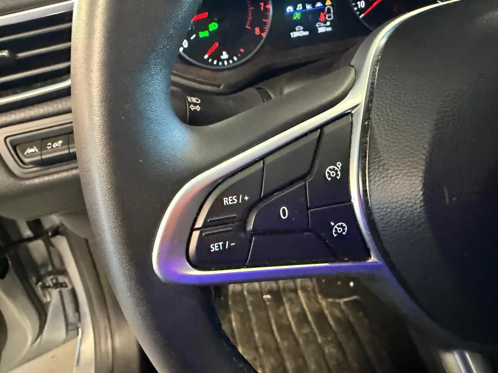 Gros plan sur le volant noir de la Renault Clio gris platine 2023, avec commandes du régulateur de vitesse visibles.