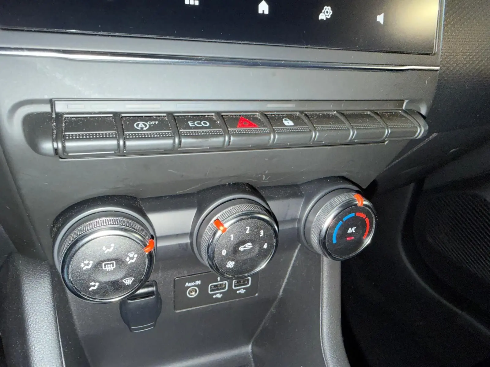 Gros plan sur la console centrale noire de la Renault Clio 2023 avec commandes climatisation et prises audio USB.