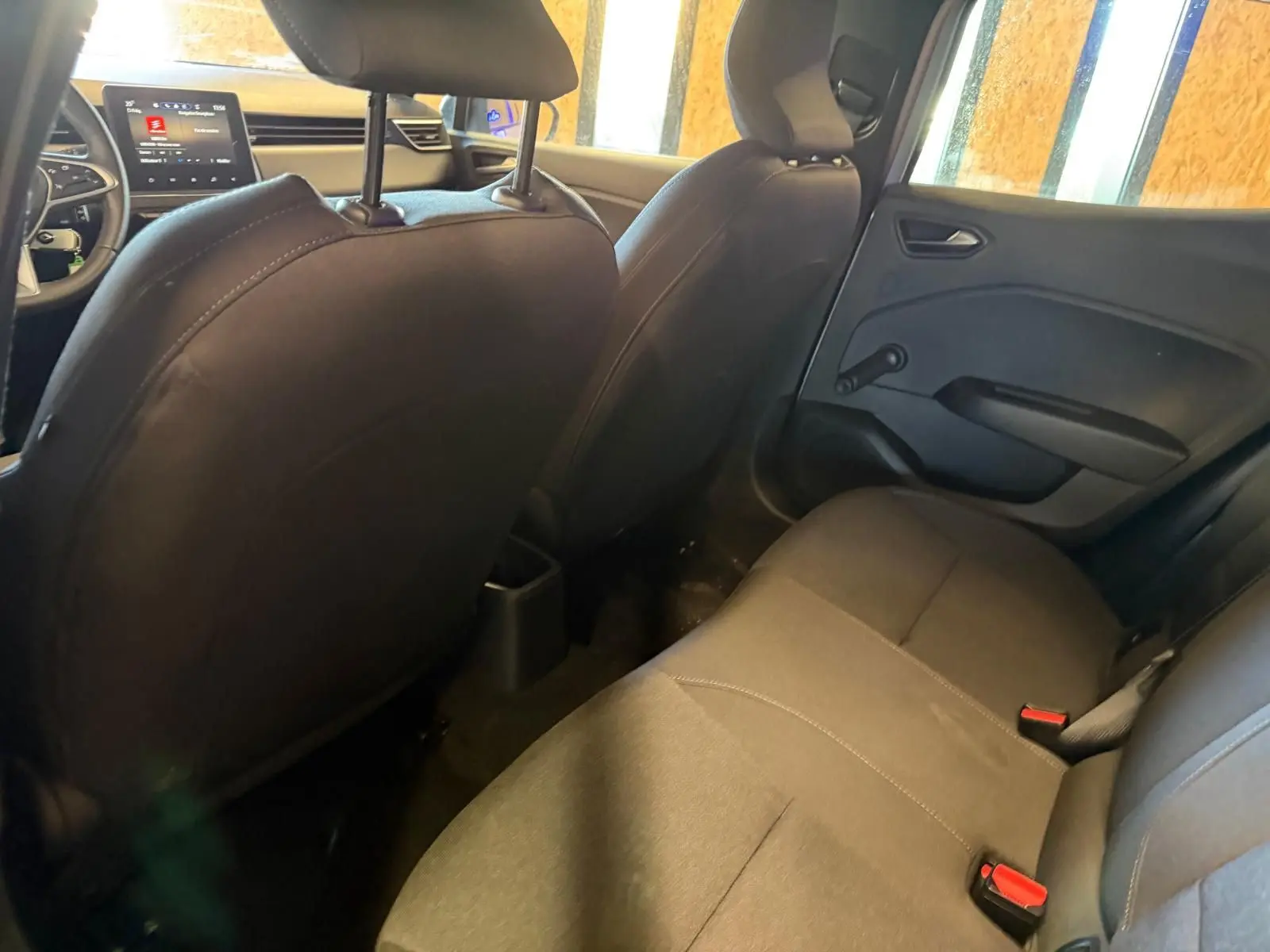 Vue intérieure arrière droite de la Renault Clio 2023, sièges noirs et banquette 1/3-2/3 avec ceintures rouges visibles.