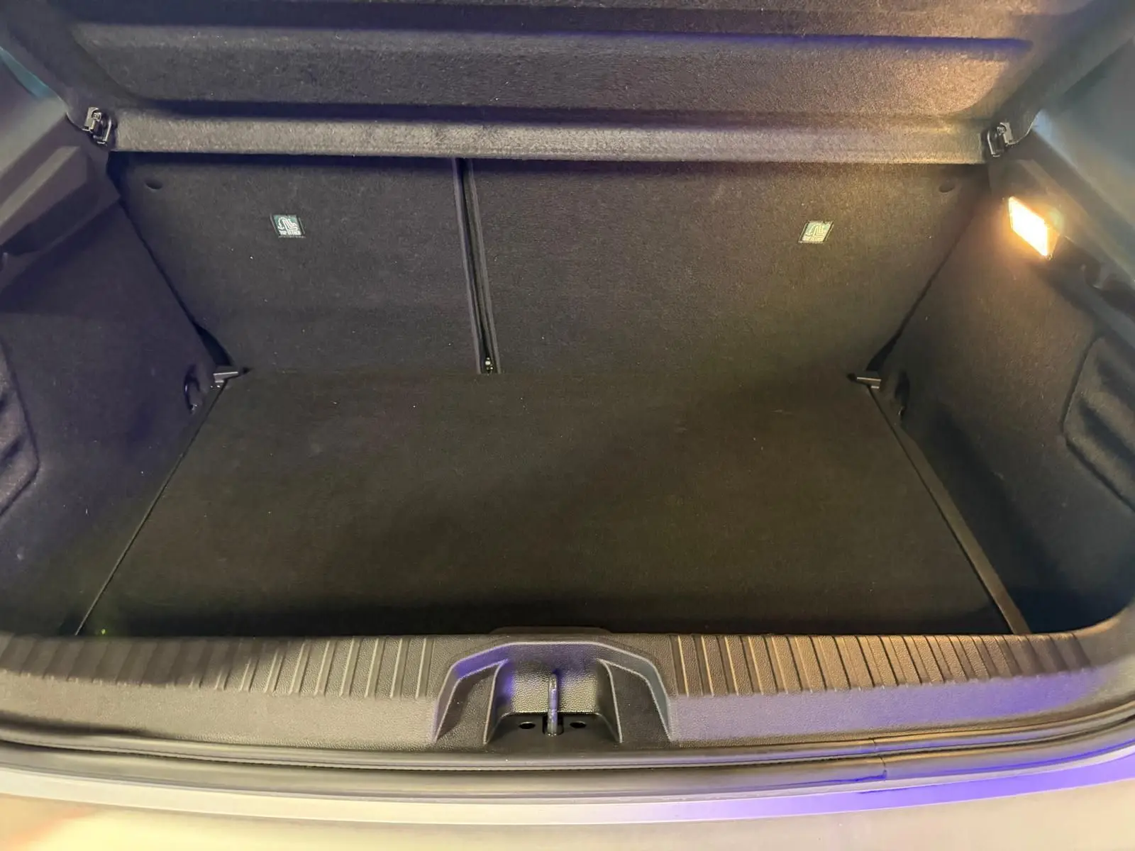 Coffre ouvert de la Renault Clio gris platine 2023, vue intérieure montrant un espace de rangement propre et éclairé.