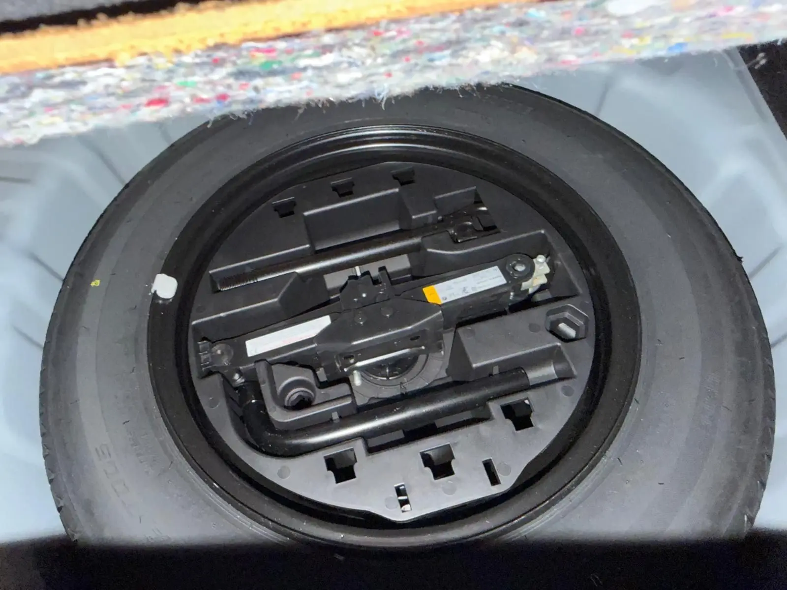 Pneu de secours avec outils de changement rangés dans le coffre d'une Renault Clio gris platine 2023.