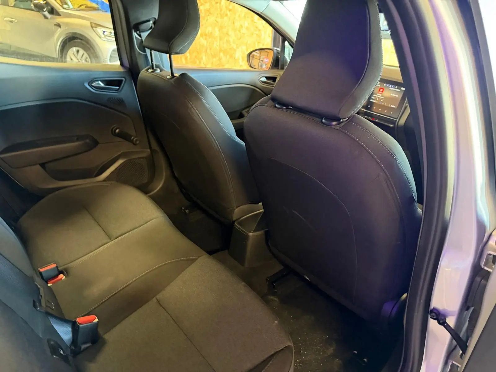 Vue intérieure arrière droite de la Renault Clio gris platine, montrant la banquette et les sièges avant noirs.