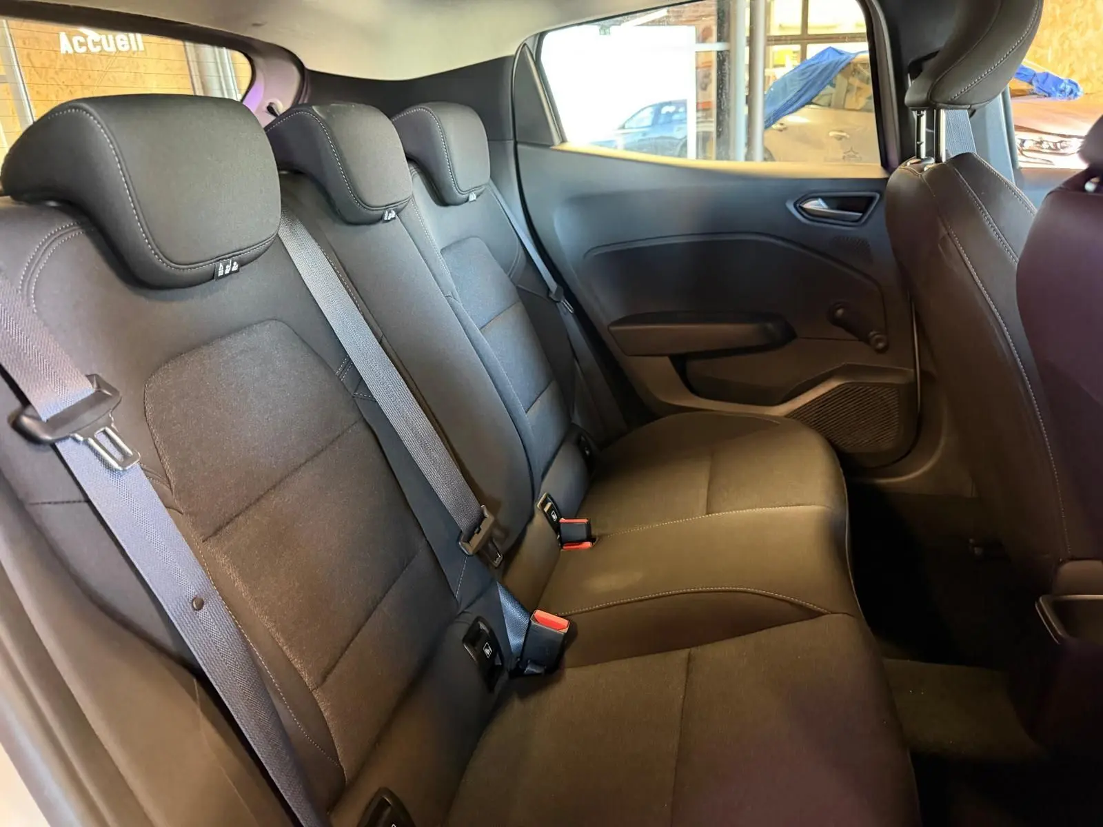 Vue intérieure de la banquette arrière noire de la Renault Clio 2023 côté droit avec ceintures et appuie-têtes visibles.