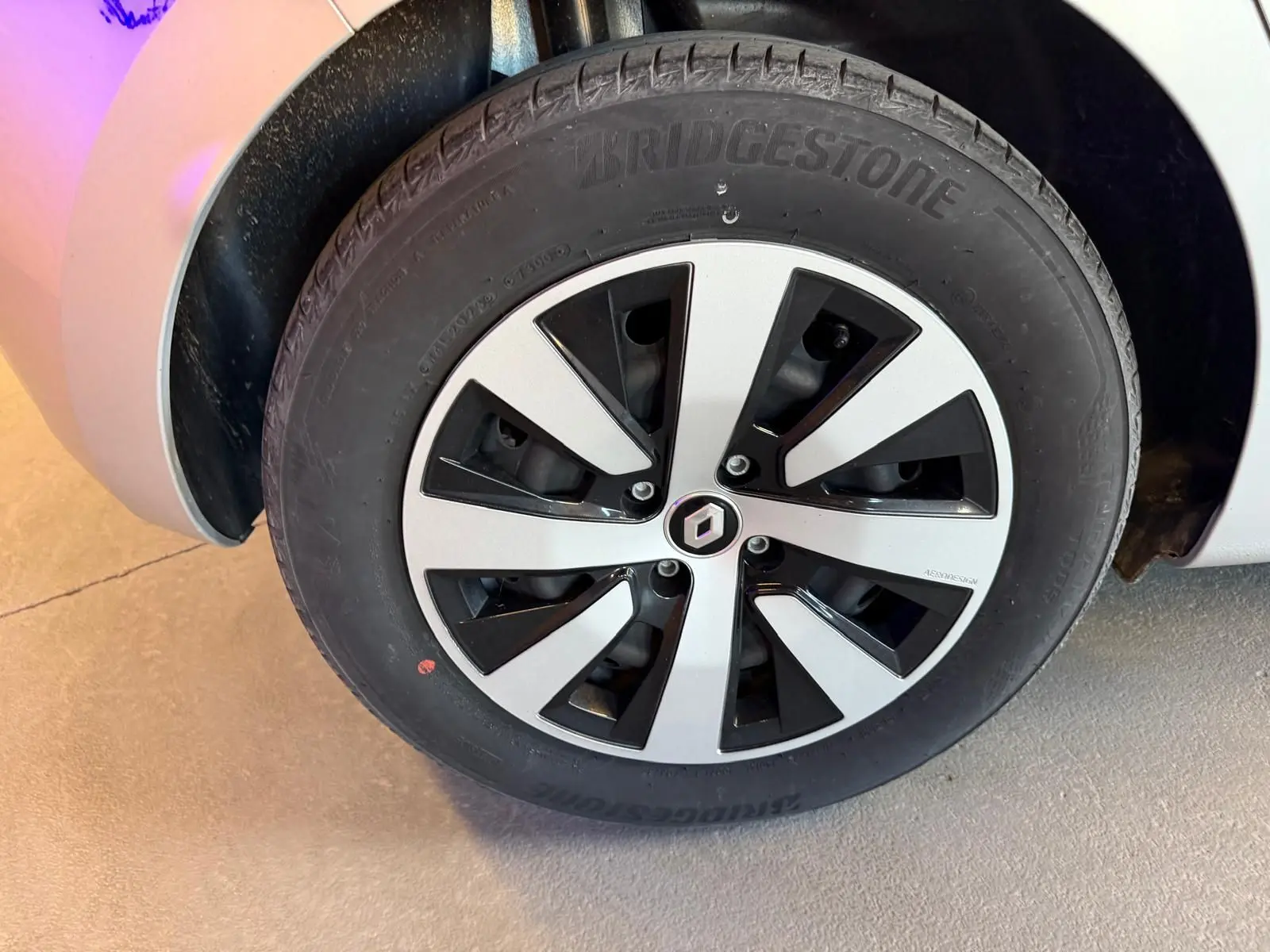 Gros plan sur la roue avant gauche gris platine d'une Renault Clio 2023 avec jante alliage bicolore et logo Renault central.