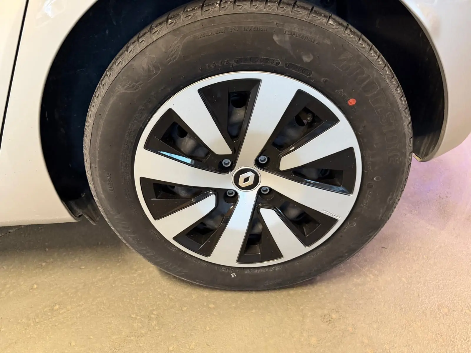 Gros plan sur la roue avant gauche d'une Renault Clio gris platine avec jante noire et argentée au design moderne.