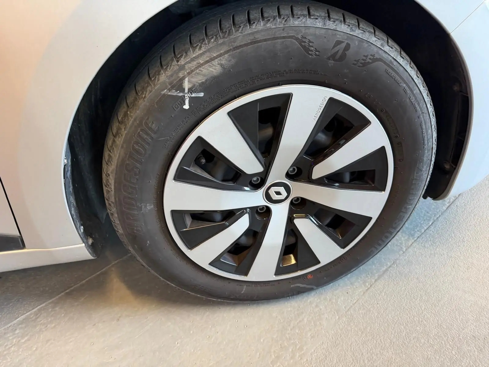 Gros plan sur la roue avant gauche grise platine d'une Renault Clio 2023 avec jante au design noir et argent.