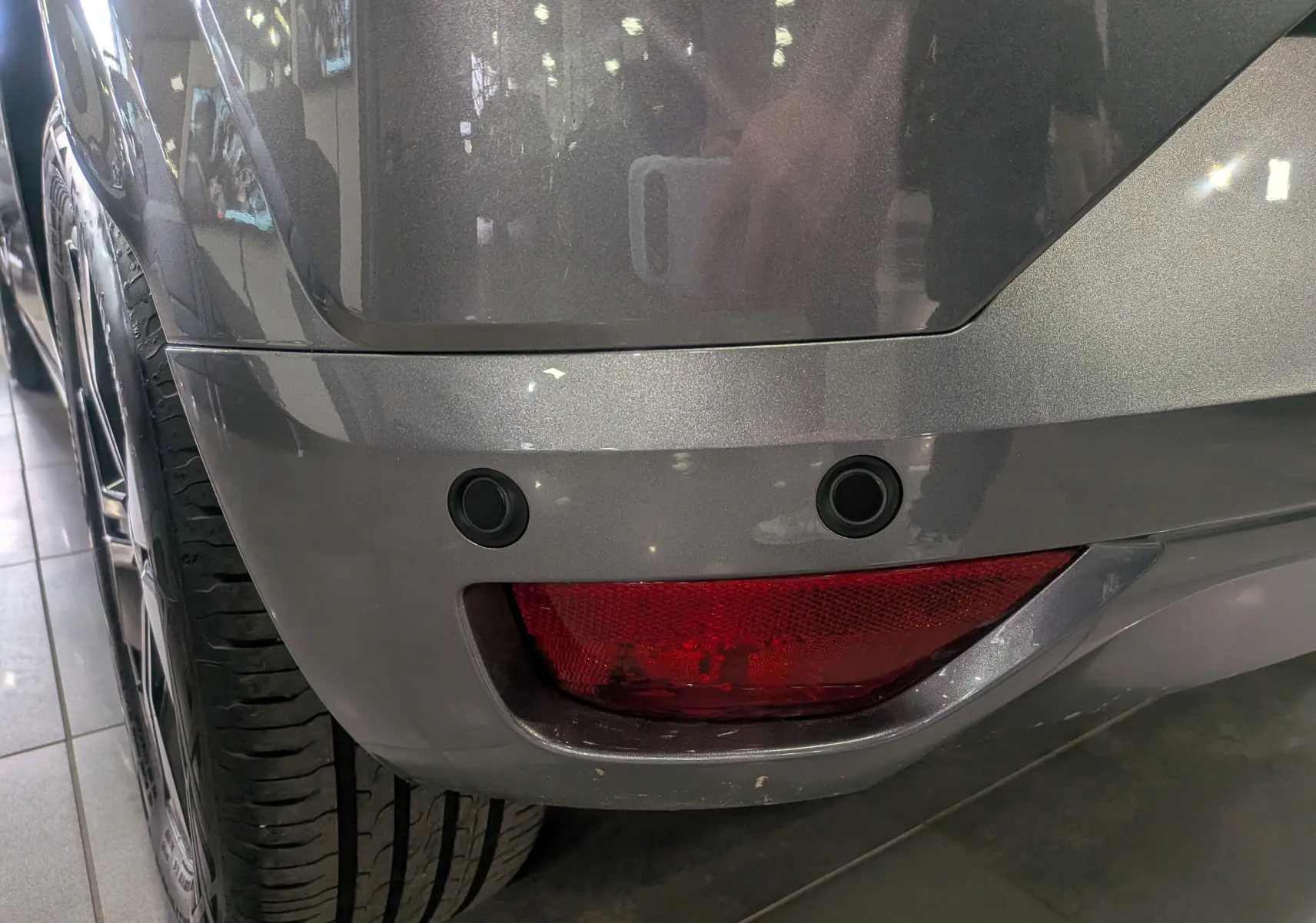 Gros plan sur le coin arrière gauche gris schiste de la Dacia Sandero 2025, avec capteurs de recul et feu antibrouillard.