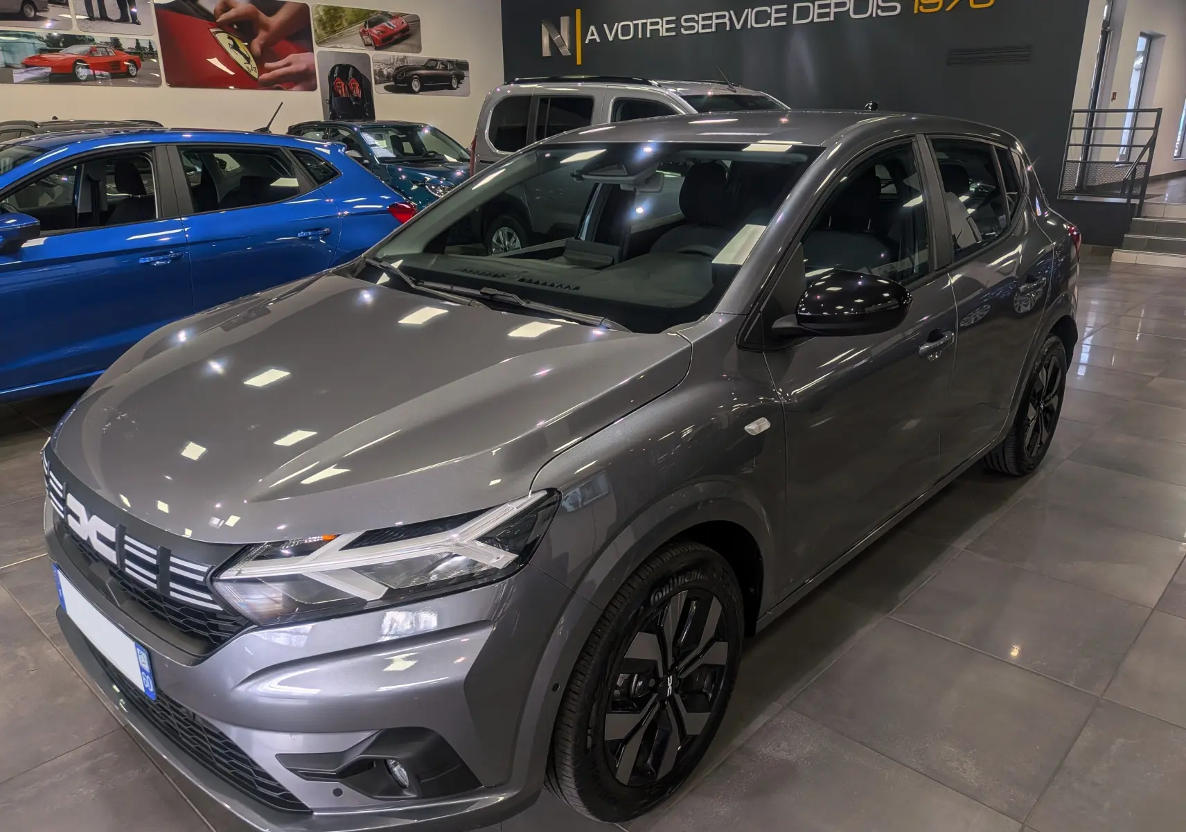 Vue 3/4 avant droite d'une Dacia Sandero TCe 90 gris schiste, avec jantes noires et rétroviseurs noirs brillants.