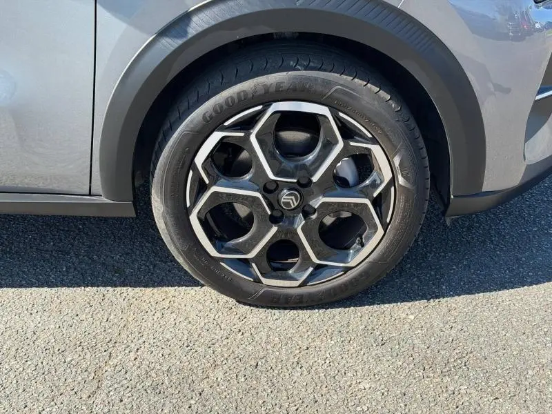 Gros plan sur la roue avant droite d'une Citroën C3 2025 gris Mercury, avec jante alliage au design hexagonal distinctif.