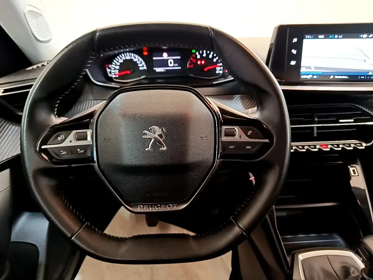 Vue rapprochée du volant cuir noir multifonctions de la Peugeot 2008 avec tableau de bord numérique et écran tactile.