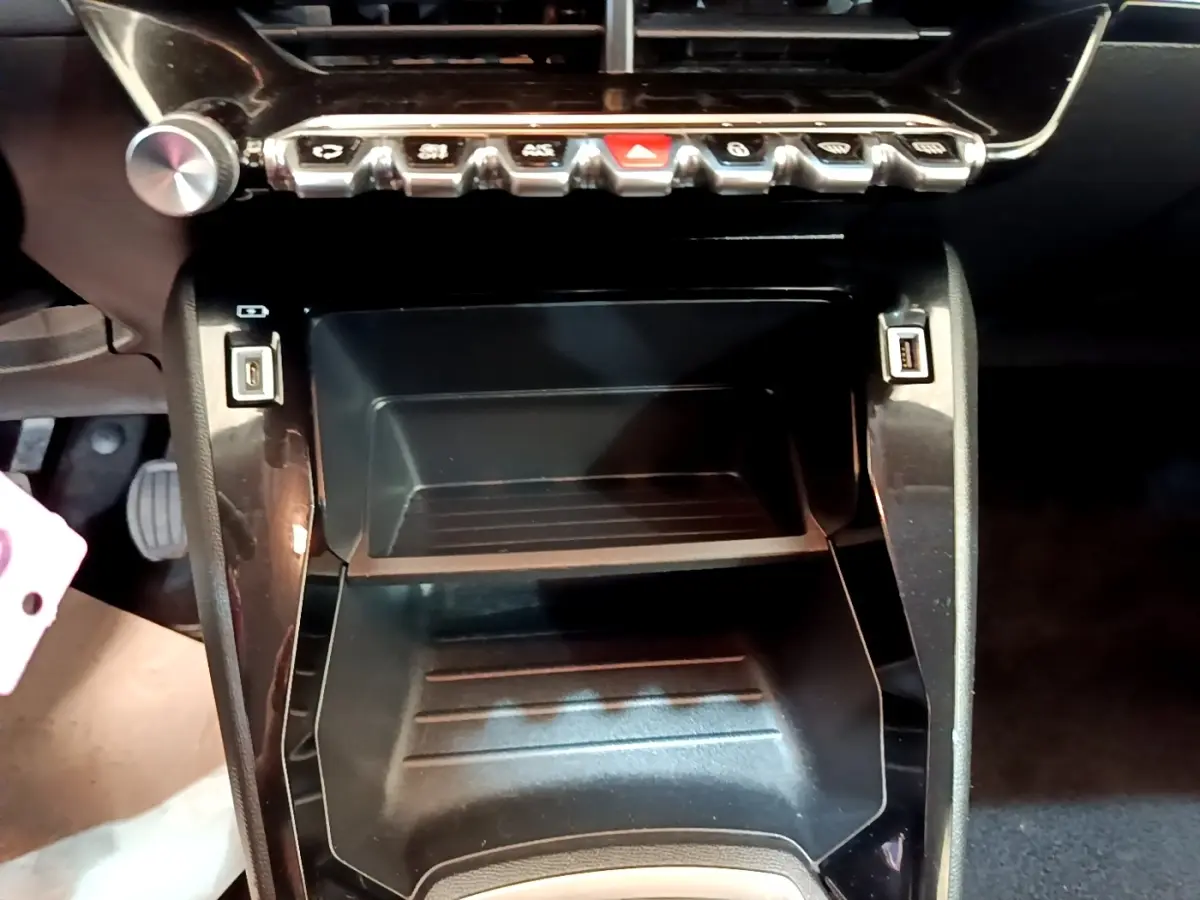 Gros plan sur la console centrale noire du Peugeot 2008 2021 avec boutons de commande et ports USB visibles.