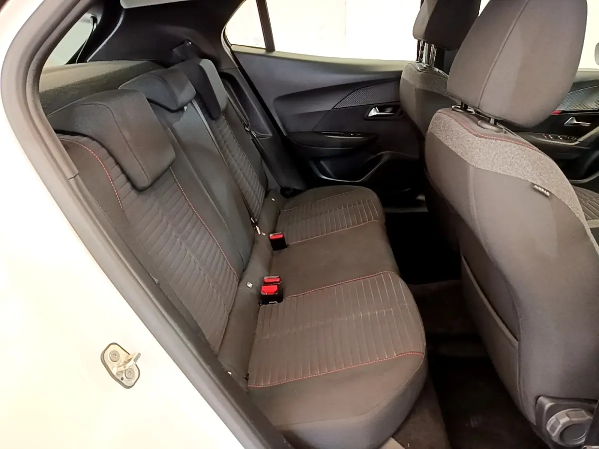 Vue intérieure côté gauche montrant la banquette arrière noire avec surpiqûres rouges du Peugeot 2008 blanc.