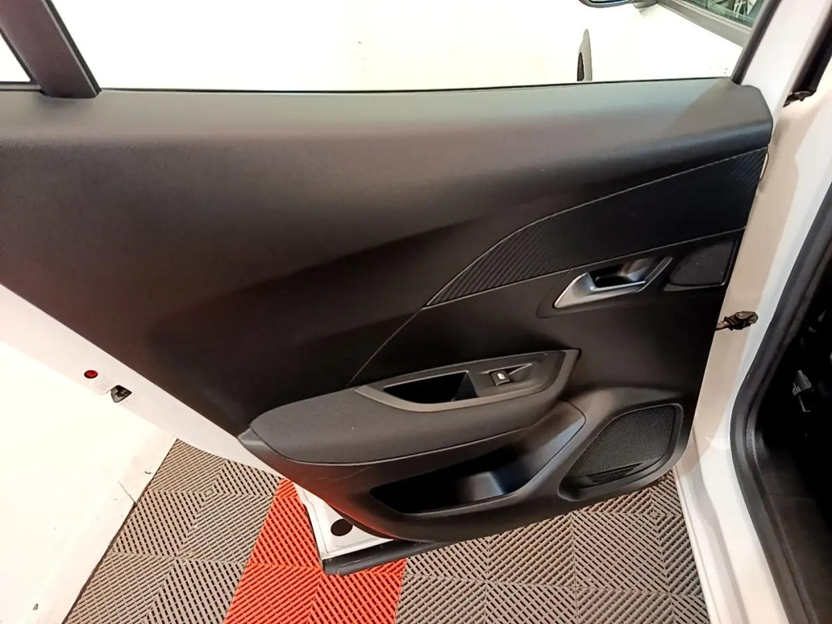 Vue rapprochée de la porte avant gauche blanche d’un Peugeot 2008 2021 avec garniture noire et commande de vitre.