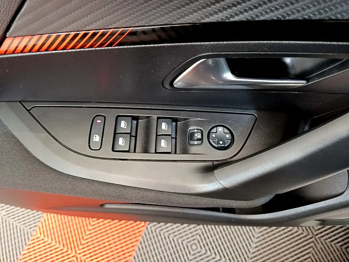 Gros plan sur la commande des vitres électriques et rétroviseurs côté conducteur d'une Peugeot 2008 blanche.