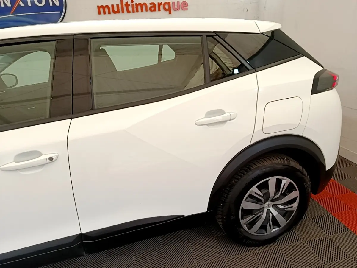 Vue latérale droite du Peugeot 2008 blanc, mettant en valeur les jantes alliage et les lignes anguleuses du profil arrière.