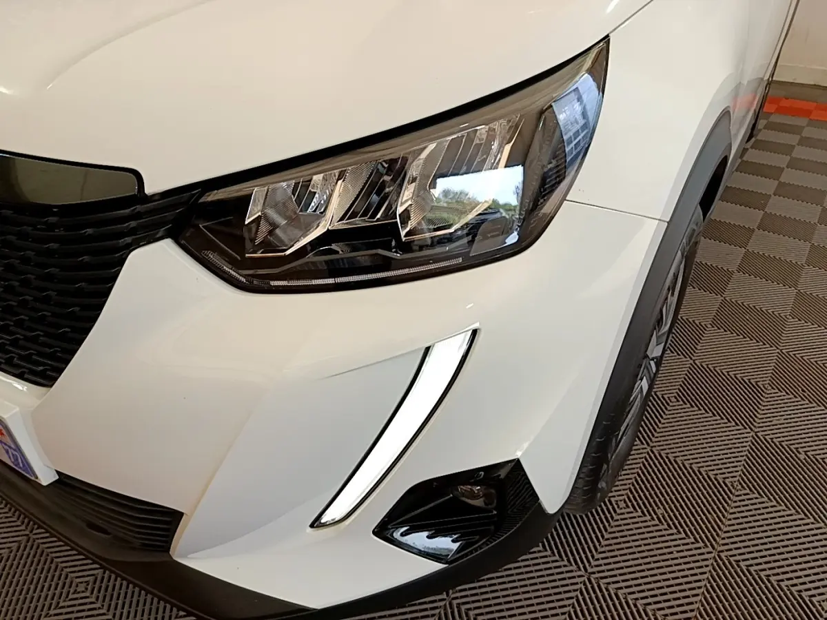 Gros plan sur l'avant droit blanc du Peugeot 2008 2021 avec phares LED et feux diurnes en forme de griffes.