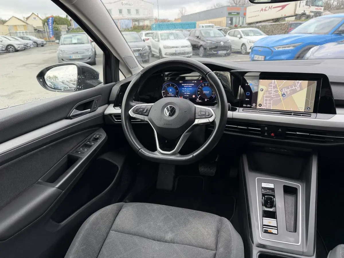 Vue intérieure avant gauche de la Volkswagen Golf SW 2.0 TDI gris, avec tableau de bord digital et écran tactile navigation.