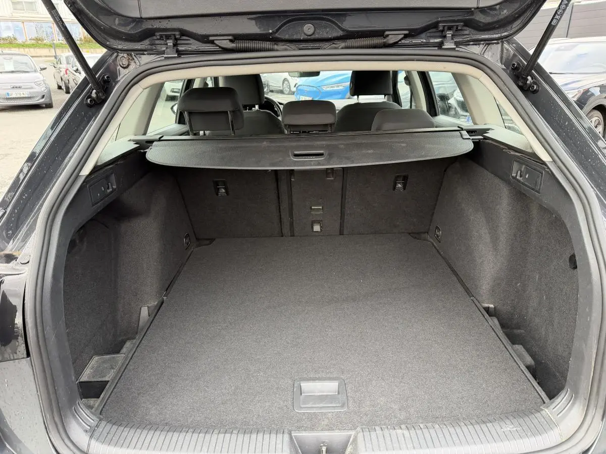 Vue arrière du coffre ouvert d'une Volkswagen Golf SW gris foncé, montrant un espace de chargement vide et la plage arrière.