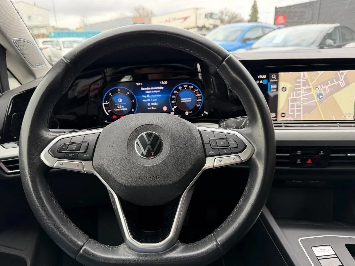 Vue rapprochée du volant multifonction noir et du tableau de bord digital de la Volkswagen Golf SW gris 2022.