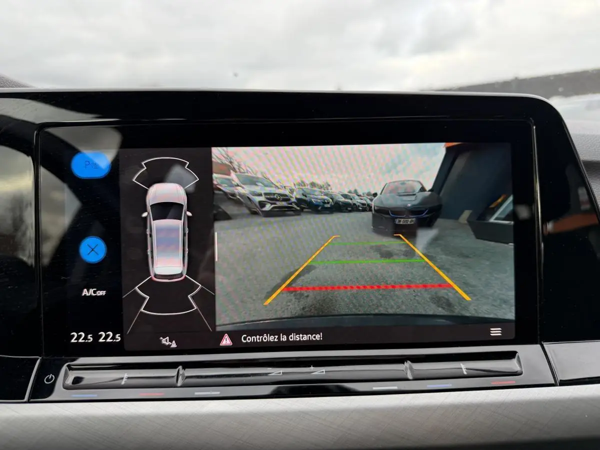 Écran de caméra de recul d'une Volkswagen Golf gris, vue arrière avec lignes de guidage colorées.
