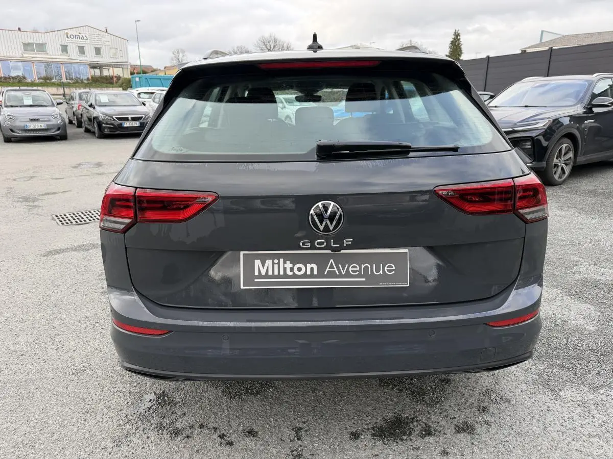 Vue arrière d'une Volkswagen Golf SW gris Urano avec feux arrière LED et plaque Milton Avenue visible.