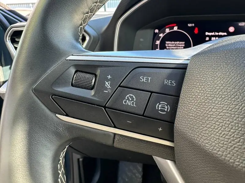 Gros plan sur les commandes au volant du SEAT LEON ST 2025, boutons de régulateur de vitesse et volume, intérieur noir.