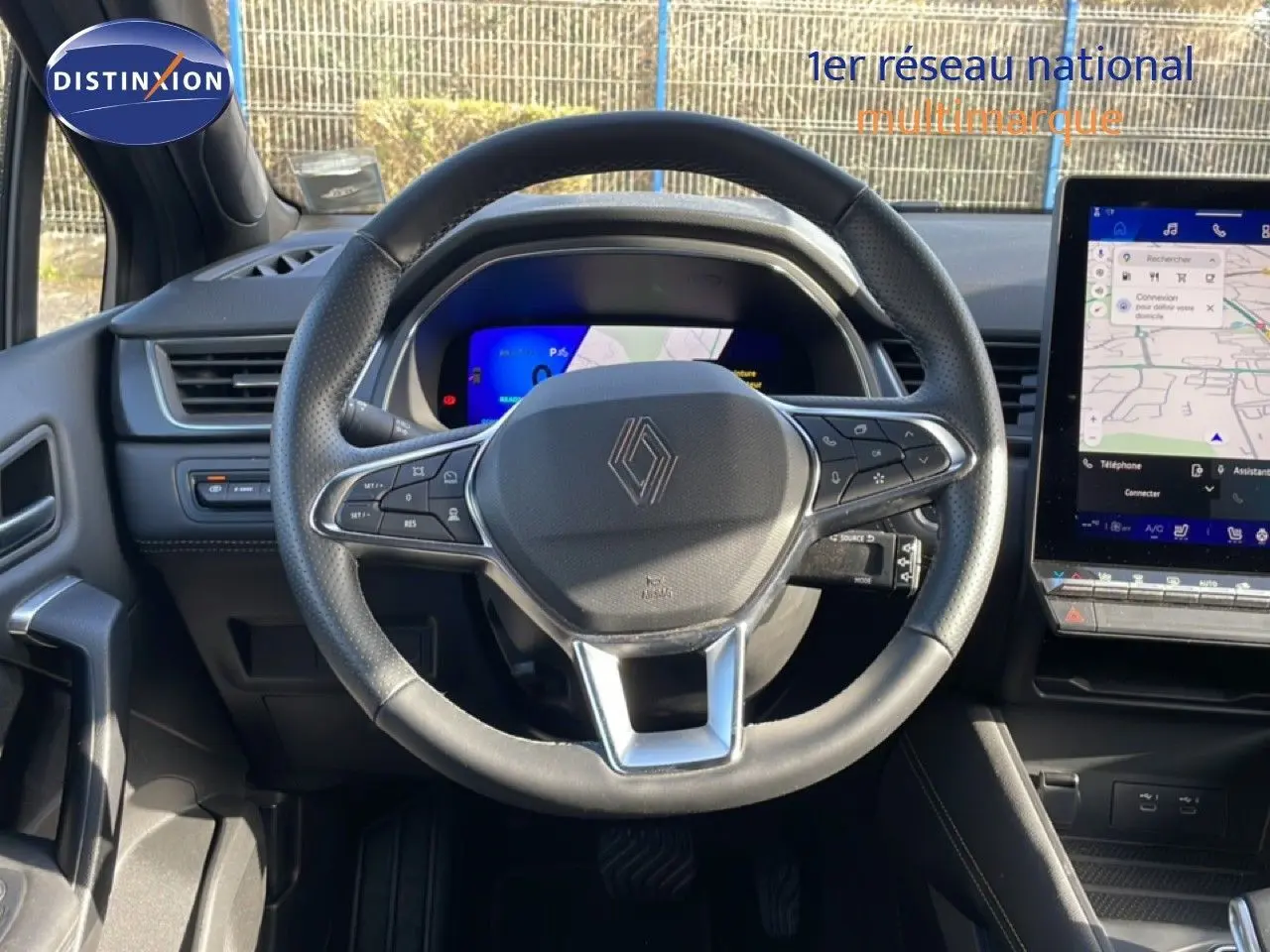 Vue intérieure centrée sur le volant noir perforé et l'écran tactile du tableau de bord du Renault Symbioz 2025.