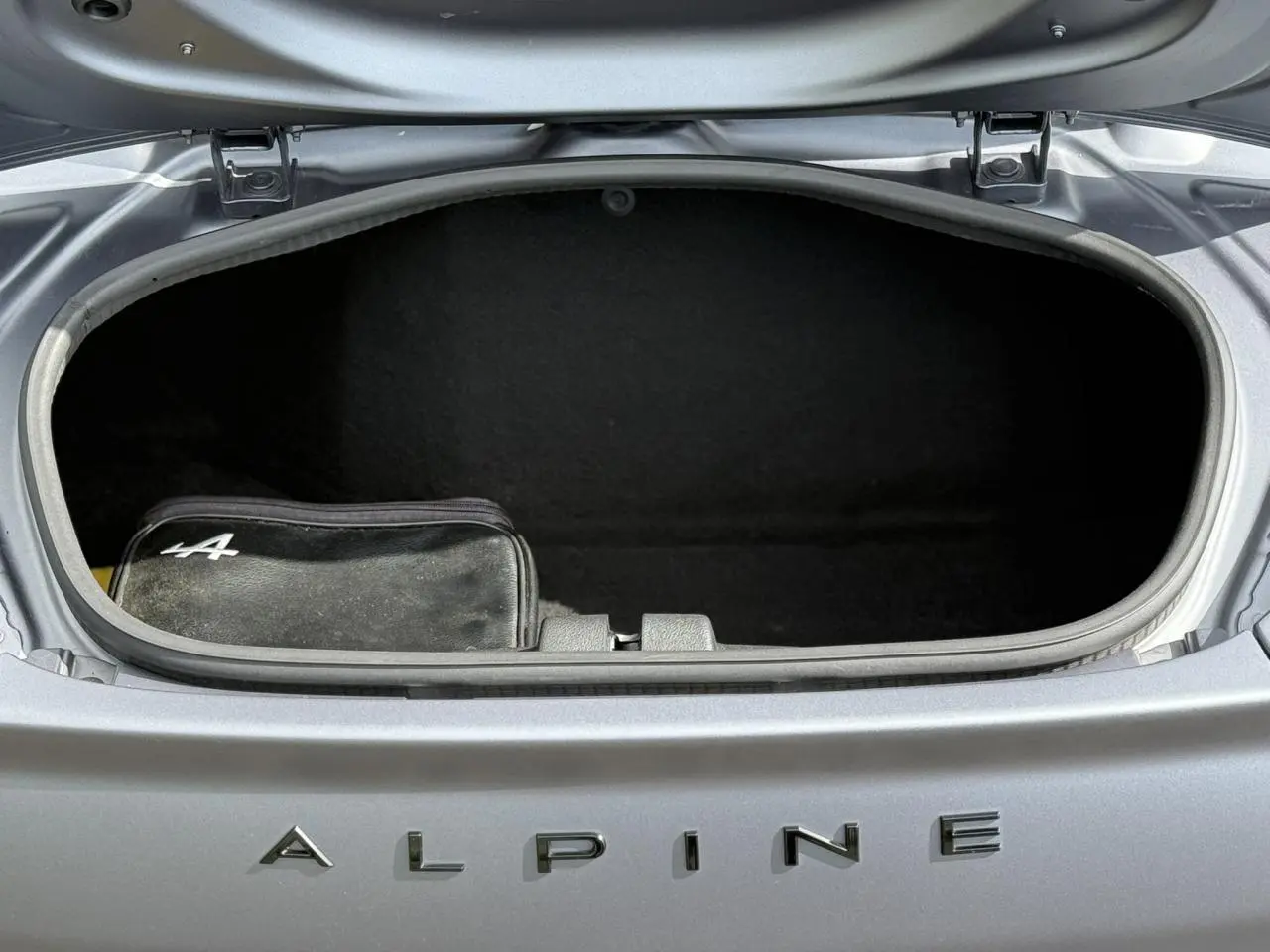 Coffre avant ouvert de l'Alpine A110 Gris Tonnerre Mat 2020, avec trousse noire marquée du logo Alpine.